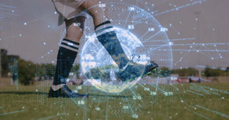 Female soccer player in knee-high socks kicking ball on pitch, holographic globe overlay with data. Athletics, technology, performance, sport, biomechanics, fitness, outdoorの写真素材