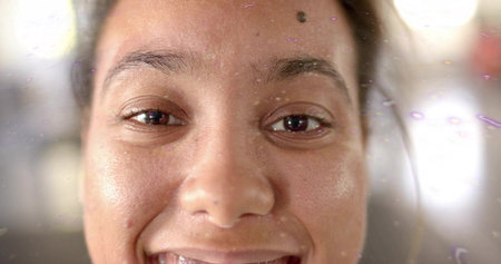 Smiling adult woman filling frame in close-up near window, with film droplets and purple glare. Portrait, headshot, studio, bokeh, texture, glow, gazeの写真素材