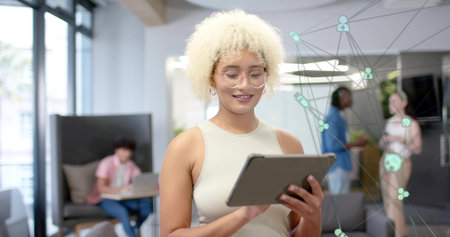 Holding woman with glasses in sleeveless beige top using tablet in office, with network overlay....