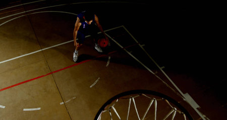 Dribbling male player wearing dark number 2 jersey on gym court, red basketball, rim, painted lines....