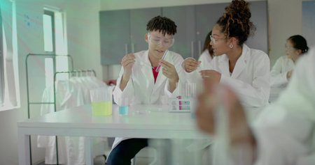 Mixing students handling test tubes with pipette at school lab bench, white lab coats and goggles....