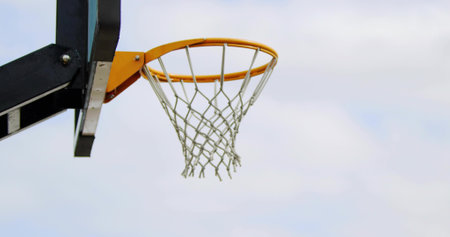 Showing basketball hoop with orange rim and white net at outdoor court left, copy space. Ring, rope,...