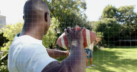Holding man wearing white tee and denim shorts preparing to throw in backyard, with football, watch. Outdoor, garden, lawn, casual, friends, sunny, sportの写真素材