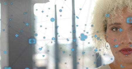 Framing adult woman gazing left by office windows, tank top, hoop earring, data overlay, copy space. Portrait, network, icons, daylight, glass, minimalist, healthcareの写真素材