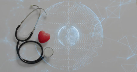 Coiling black stethoscope around red heart on pale gray table, showing digital globe, copy space....