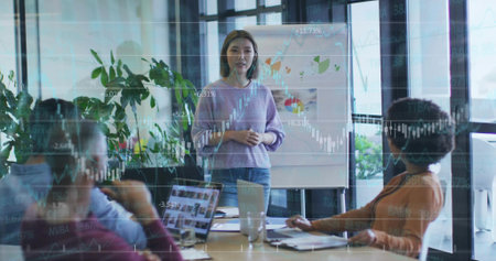 Presenting Asian woman explaining flip chart graphs in conference room, with stock market overlay. Corporate, teamwork, collaboration, professional, modern, innovation, analyticsの写真素材