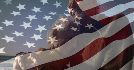 Hugging senior couple wearing knit sweaters on beach, with rolling ocean waves. Romance, serenity, autumn, companionship, minimalism, gratitudeの写真素材