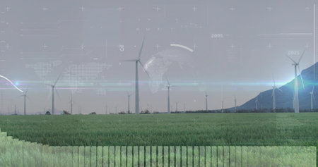 Rotating wind turbine tower spinning above grassy field near mountain ridge with digital overlay....