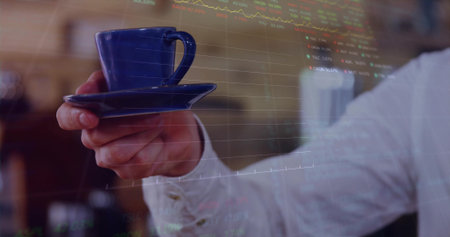 Holding cuffed hand presenting blue ceramic coffee cup with saucer in cafe showing stock charts. Business, finance, modern, sophisticated, workspace, professional, tradingの写真素材