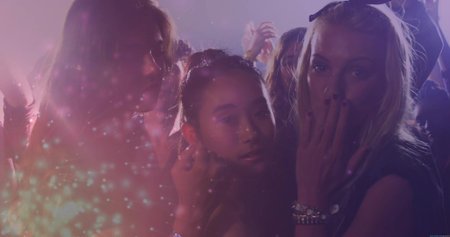 Dancing three friends pressing close on club dancefloor, showing bracelets under purple strobe haze. Nightlife, celebration, vibrant, energetic, party, social, glowの写真素材