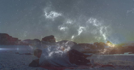 Hugging couple lying close together on sandy beach shore at dusk, with small blanket. Romance,...
