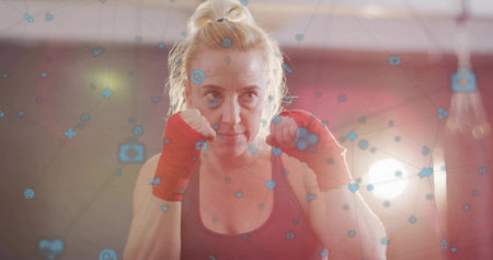 Standing boxer holding fists in boxing gym, with dark tank top, red wraps. Fitness, empowerment, strength, sport, training, dynamic, modernの写真素材
