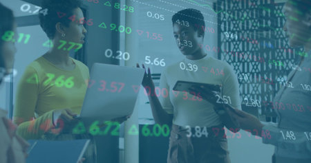 Discussing four women analyzing floating financial data overlay in office area, with laptops tablet. Collaboration, innovation, technology, business, analytics, modern, teamworkの写真素材