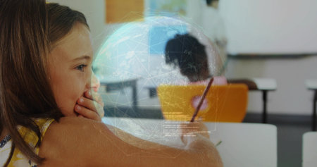 Thinking girl in yellow top gazing at desk in classroom with globe overlay, copy space. Education, learning, technology, innovation, classroom, student, collaborationの写真素材