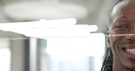 Smiling man with dreadlocks wearing dark top facing camera in office, waveform overlay, copy space. Portrait, headshot, backlit, highcontrast, workspace, modern, analyticsの写真素材