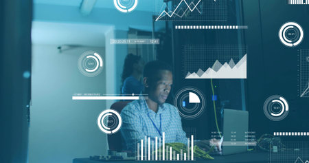 Mid adult man wearing blue shirt monitoring data charts in server room, with laptop, server rack....