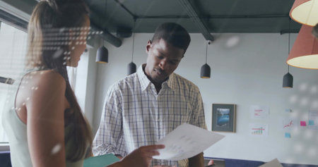 African American man and colleague reviewing printed document in office, with charts and notes....