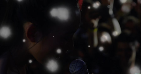 Performing Chinese singer holding mic on concert stage, with lit orbs and stage lights copy space....