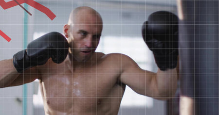 Punching shirtless bald man delivering punch on heavy punching bag in gym, with black boxing gloves....