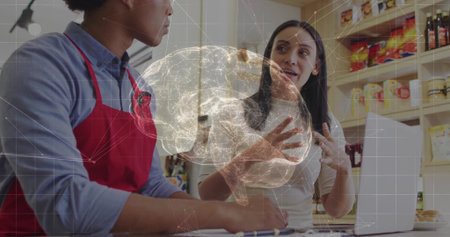 Discussing coworkers wearing red apron and white top at cafe, with laptop. Collaboration, teamwork, technology, innovation, hospitality, modern, professionalの写真素材