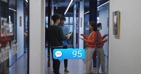 Reviewing three coworkers consulting documents and tablet in glass corridor, with yellow folder. Collaboration, teamwork, modern, professional, innovation, productivity, officeの写真素材