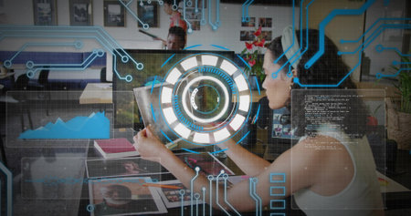 Reviewing woman analyzing tablet interface at open-plan office, with coffee mug and photographs. Collaboration, workspace, innovation, technology, contemporary, productivity, diversityの写真素材