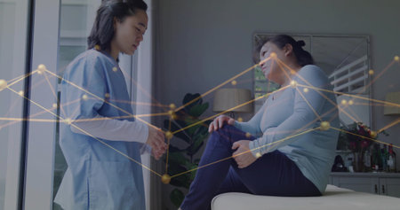 Consulting scrub-clad nurse observing male patient touching knee in clinic room, with exam table. Medical, healthcare, wellness, therapy, clinical, caring, professionalの写真素材
