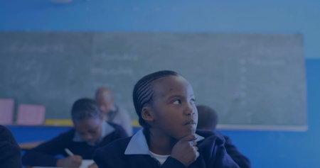 Resting chin on hand uniformed girl gazing to right in classroom, with chalkboard and notebooks. Education, study, learning, academic, youth, classroom, concentrationの写真素材