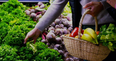 Reaching shopper grabbing lettuce in produce section with basket holding bananas, herbs, copy space. Fresh produce, grocery shopping, urban market, organic vegetables, healthy lifestyle, natural foodの写真素材