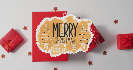 Image of merry christmas text over presents and christmas decorations on white background....