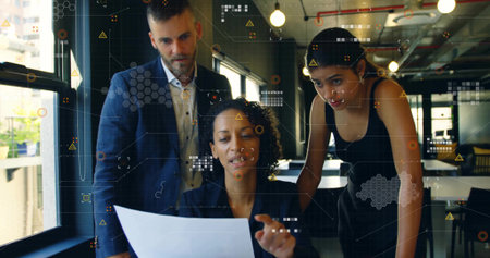 Manager in dark blazer reviewing printed report with colleagues in open office, with data graphics. Collaboration, teamwork, modernoffice, corporate, professional, dataanalysis, innovativeの写真素材