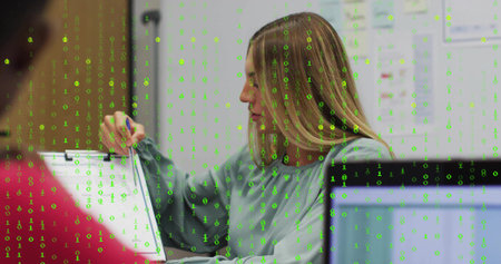 Pointing woman with blonde writing on clipboard in meeting room, with green binary code overlay. Business, collaboration, analytical, modern, technology, professional, dataの写真素材