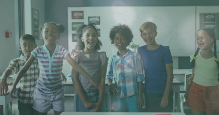 Smiling classmates standing and raising arms in classroom, with desks chairs whiteboard posters. Student, education, learning, teamwork, school, discovery, youthfulの写真素材