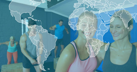 Two women in sportswear jumping onto wooden plyometric boxes in gym studio, with metal pull-up rig. Fitness, athleticism, training, exercise, strength, motivation, gymの写真素材