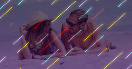 Lying couple wearing straw hat, dark sunglasses, bikini, trunks on sandy beach with neon streaks....