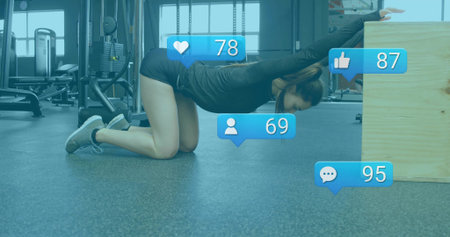 Kneeling athlete stretching arms on rubber floor in gym, with plyometric box and social overlays....