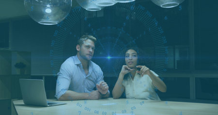 Collaborating man and woman in business casual at conference table, reviewing report with laptop. Professional, teamwork, brainstorming, modern, corporate, productivity, communicationの写真素材