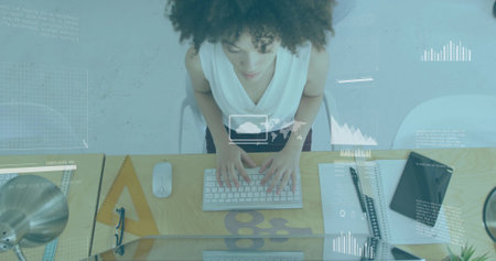 Typing woman in white sleeveless top at office desk, with wireless keyboard and graphics overlay. Technology, data analysis, workspace, professional, productivity, modern, innovationの写真素材