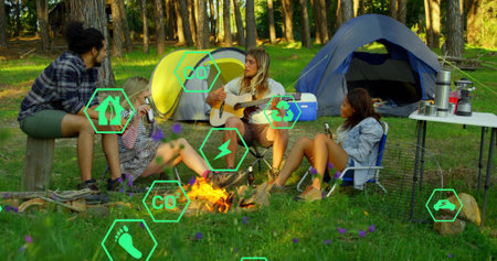 Gathering friends strumming guitar around campfire in pine woods clearing, with stove and cooler. Outdoor, leisure, nature, relaxation, adventure, rustic, harmonyの写真素材