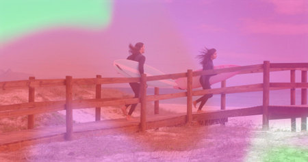 Walking couple wearing wetsuits and carrying surfboards on boardwalk by dune grasses toward ocean. Adventure, coastal, minimalist, lifestyle, leisure, nature, activeの写真素材