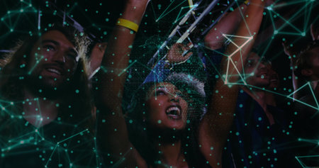 Cheering woman wearing bucket hat, wristbands raising arms at night concert, friends holding phones. Concert, nightlife, celebration, energy, crowd, festival, illuminationの写真素材