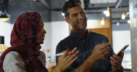 Pointing at board, colleagues wearing headscarf and shirt holding marker and smartphone at office. Collaboration, teamwork, modern, professional, communication, brainstorming, workplaceの写真素材