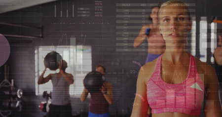White woman wearing pink sports bra holding medicine ball in gym studio, with earphones, copy space. Fitness, exercise, camaraderie, strength, athletic, wellness, trainingの写真素材