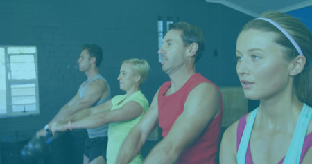 Swinging kettlebells four adult fitness participants working out in gym studio, with wooden boxes. Fitness, strength, teamwork, dynamic, wellness, training, vibrantの写真素材