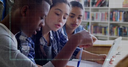 Collaborating students leaning over notebooks and laptop at school library table, with bookshelves. Collaboration, education, teamwork, study, youth, learning, academicの写真素材