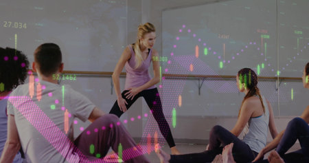 Instructor guiding participants through wide legged pose in studio, with financial chart overlays....