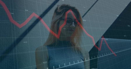 Analyzing data on red graph, woman standing in office lobby with gridlines, beams and glass panels. Business, technology, modern, corporate, analytics, innovation, digitalの写真素材