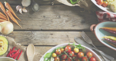 Displaying white bowl holding cherry tomatoes and greens on rustic wooden tabletop, with spoon. Farmhouse, produce, vegetables, kitchen, utensils, textiles, colorfulの写真素材