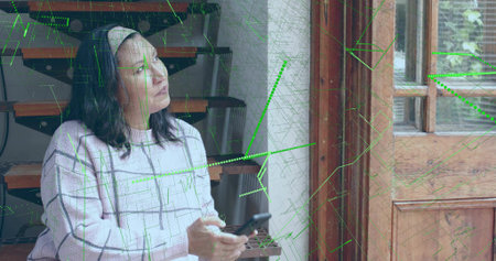 Holding smartphone, mature woman gazing toward light by wooden doorway, in checked sweater, overlay....