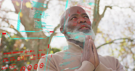 Praying senior man wearing tan zip-up sweater holding hands near chin among trees, with AR panels....